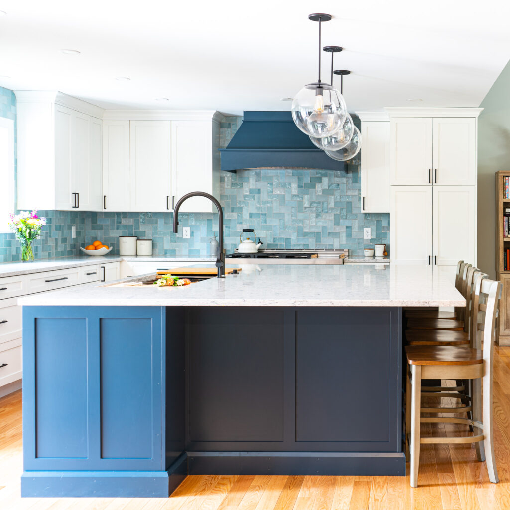 Kitchen cabinetry and island made of maple made using the Mission door style. The cabinetry is painted in a snow finish and the island is painted in a gale force finish